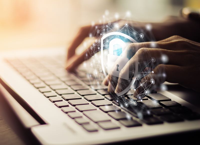 Photo of hands typing on a keyboard with a digital image overlay of a padlock and social network to represent online security.