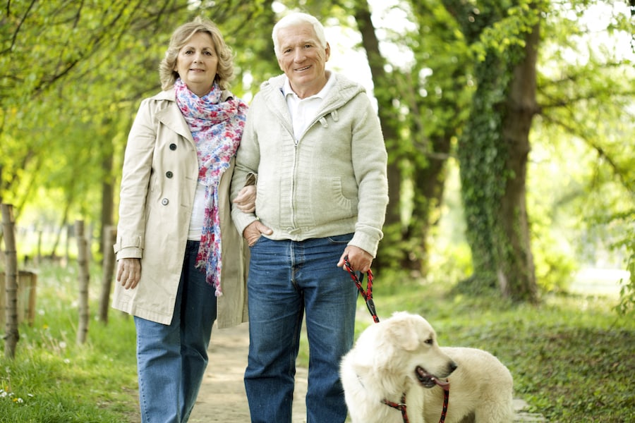 Senior couple enjoys walking their dog and getting some exercise along an open space trail